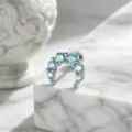 Close-up detail of moon-shaped ear piercing stud with sparkling light blue crystals - Moon Style (A-1031) / Stainless Steel External Spiral / Blue