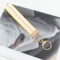 Detailansicht eines gelb-rosa gewebten Stoff-Schlüsselanhängers mit Gold-Hardware - Gelber Rand Goldener Verschluss