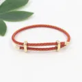 Primer plano de una pulsera de cuerda trenzada roja con hebilla dorada ajustable. - Rojo Dorado