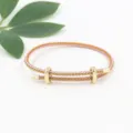 Detalle de pulsera de cable trenzado rosa y dorado con cierres deslizantes. - Rosa Dorado