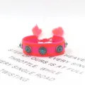 Detailansicht eines handgewebten Ethno-Armbands mit Türkis-Nieten und rosa Quasten - Stil 5