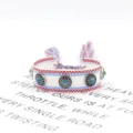 Nahaufnahme eines handgewebten Ethno-Armbands mit Metallnieten und blauen Türkissteinen - Stil 18