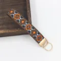 Detailaufnahme eines böhmischen gewebten Schlüsselanhängers mit goldenen Metallakzenten - Orange Rhombus Geometrisch (E)