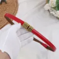 Red patent leather thin belt for women with chic gold metal charm, versatile waist accessory. - Glossy Red