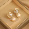 Nahaufnahme eleganter Rosenohrringe mit glänzendem Zirkonia-Herz und Champagner-Perle. - Emaille Blume Perle Ohrringe