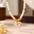 Nahaufnahme des eleganten Blumenanhängers mit Zirkon-Mikrofassung auf Perlenkette. - Blumenanhänger / Gold