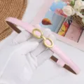 Dettaglio di cintura sottile da donna in pelle verniciata rosa con fibbia ovale dorata chic. - Rosa Lucido