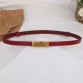 Dettaglio cintura in pelle rossa, cinturino sottile con chiusura metallica dorata in vita. - Rosso