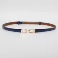 Close-up detail of a slim navy blue leather belt with an elegant gold buckle, perfect accessory. - Glossy Blue