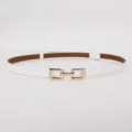 Detailed view of women's thin white leather dress belt featuring an elegant golden metal buckle. - Glossy White