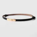Dettaglio di una sottile cintura in pelle nera da donna con elegante fibbia metallica. - Nero