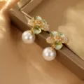Nahaufnahme eleganter grüner Emaille-Blumenohrringe mit weißen Perlen-Anhängern. - Grüne Blume Perle Ohrringe