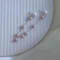 Nahaufnahme eleganter langer Quastenohrringe mit rosa und weißen Perlen an Silberketten - Perlenohrstecker