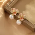 Nahaufnahme eleganter Blumen-Perlenohrringe mit rosa Emaille und funkelnden Kristallen. - Rosa Blumen-Perlenohrringe