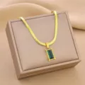 Macro view of golden titanium steel snake chain with elegant emerald green pendant - Gold Green Diamond / Gold