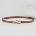 Detailed view of the women thin brown leather belt featuring a stylish gold heart metal buckle. - Caramel color