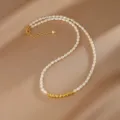 Nahaufnahme einer Naturperlenkette mit eleganten goldenen zylindrischen Akzenten. - Halskette