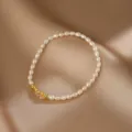 Detailansicht eines eleganten Armbands aus weißen Naturperlen mit goldenen Metallperlen - Armband