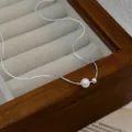 Nahaufnahme einer minimalistischen Halskette mit einer weißen Perle an einer feinen Silberkette - Süßwasserperle 2
