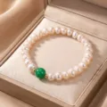 Close-up of a natural pearl bracelet with a green stone bead in a beige jewelry box - Style 8