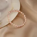 Macro detail shot of a natural pink freshwater pearl bracelet on satin with a seashell - Style 6