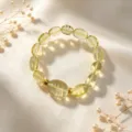 Detaillierte Nahaufnahme eines natürlichen Citrin-Kristallarmbands auf elegantem weißem Satin - Hellgelber Transparenter Ovalperlen-Stil mit Goldenen Distanzstücken (款16)