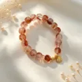 Detaillierte Nahaufnahme von Erdbeerquarzperlen und goldenem Anhänger auf Seide - Herzanhänger Erdbeerquarz Armband (Stil 29)