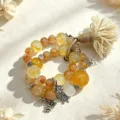 Detailansicht von Naturkristall-Perlenarmband mit Quaste und Schmetterlingsanhängern. - Gelb-Bernsteinfarbener Schmetterling (Stil 13)