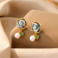 Elegante blaue Emaille-Blumenohrringe mit weißer Perle und Zirkonia-Akzenten in Gold - Kamelien Perlen Ohrstecker