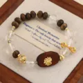 Natürliches Adlerholz- und Kristallperlenarmband mit goldenem Lotus-Anhänger auf Holztablett. - Lotus-Holzplatte Zen-Stil / Dunkelbraun