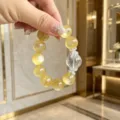 Nahaufnahme eines Armbands aus goldenem Lepidolith mit transparentem Kristall - Hohler Blumenzwischenperle Stil (Stil 7)