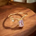 Primer plano de un anillo en V dorado con una radiante amatista púrpura rectangular engastada - Talla 5 (US) / Anillo de amatista