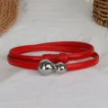 Dettaglio in primo piano di sottile cintura in pelle rossa con doppie fibbie sferiche. - Chiusura in Argento Rosso