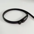 Primo piano dettagliato di una sottile cintura in pelle marrone scuro e minimalista. - Caffè (solo cinturino)