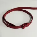 Vista dettagliata di una cintura sottile in pelle rossa con cuciture fini e liscia. - Rosso