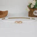 Dettaglio di una elegante cintura sottile bianca da donna con fibbia decorata di perle. - Bianco