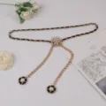 Detail view of a luxury gold chain belt featuring black leather weave and pearl flower pendants. - #291 Black