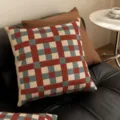 Primo piano di un cuscino decorativo a quadri rossi e blu, che aggiunge stile al divano. - 35x35 cm (senza interno cuscino) / SBZA041802