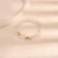Primo piano del braccialetto in quarzo fragola e agata bianca con ciondolo a zampa di gatto. - Giada Bianca