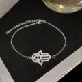 Bracelet Hamsa en acier titane argenté avec œil protecteur et pierres de zircone - Style de main mauvais œil argenté (Style 20)