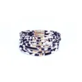 Primer plano de la pulsera de cuero con estampado de leopardo en blanco y negro y tubos dorados. - Patrón de Vaca