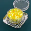 Close-up van gele iriserende zeshoekige glittervlokken voor nail art en DIY - Pot / Fantoom geel