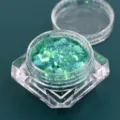 Macro close-up van groene iriserende grove glitter in een helder gefacetteerd potje - Pot / Iriskaderend groen