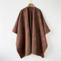 Vista de cerca muy detallada del poncho de punto marron con patron para la temporada. - Tótem Tierra Roja