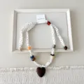 Gedetailleerd overzicht van een stoffen ketting met stippen, kleurrijke kralen en houten hart. - 05 Hart - kleine stippen beige