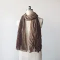 Detailansicht eines braunen, verlaufenden, geknitterten Leinenschals für modisches Styling. - Kaffee