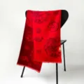 Detail shot of a festive red scarf featuring traditional dragon and coin patterns draped on a chair. - MYRM011-Auspicious Dragon Blessing
