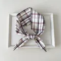 Detailaufnahme des klassischen karierten Haarbandes mit feiner Stoff- und Webstruktur. - 33 Spitzes Ende - Braun-rote Karos