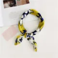 Detail shot of a stylish yellow and blue silk square scarf with chic floral print patterns. - Small Yellow Flower