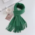 Close-up detail of a soft green winter cashmere-feel tassel scarf on clean white tabletop. - Emerald Green